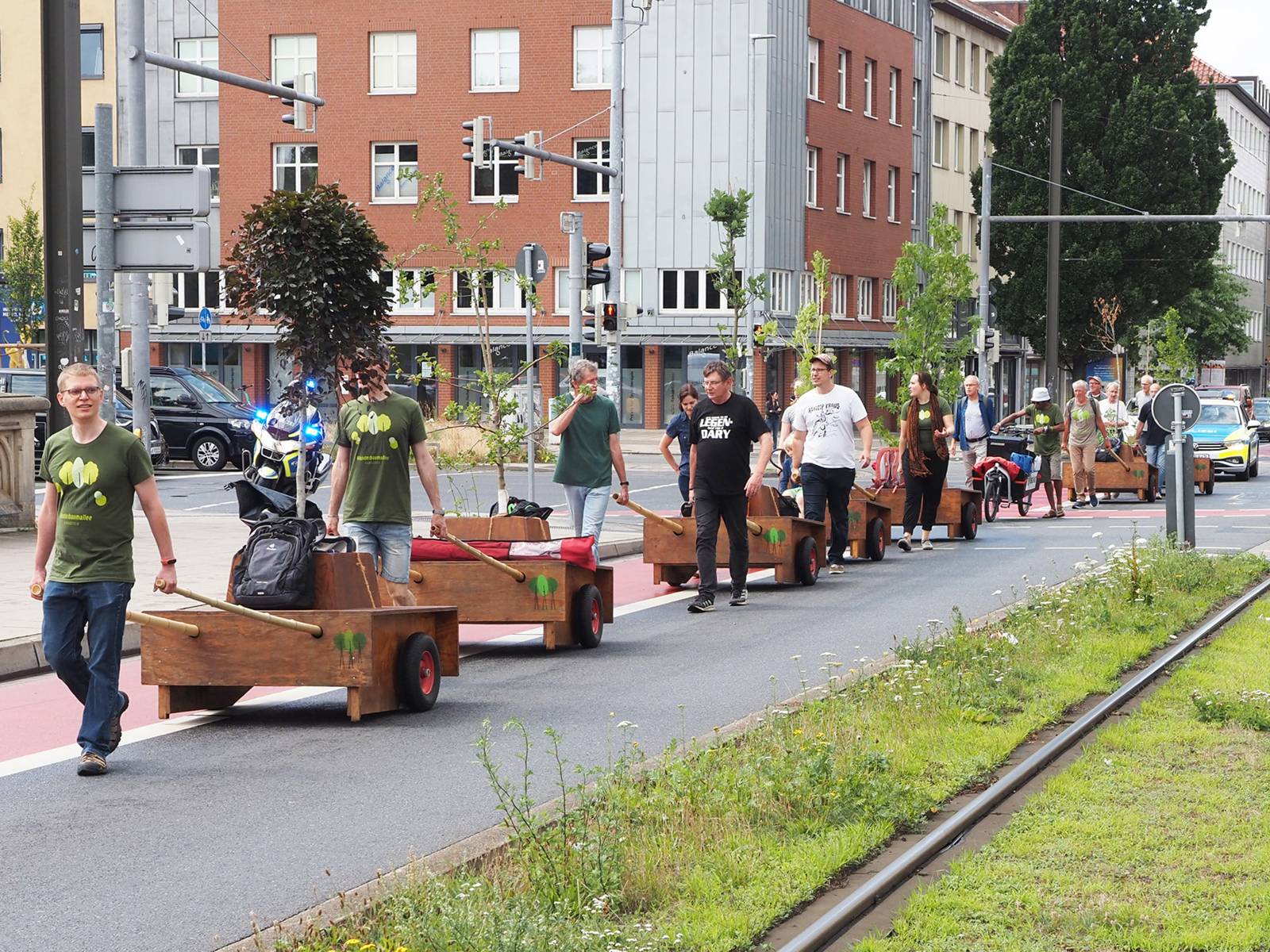 Mehrere Menschen, die Bäume durch Hannovers Straßen bewegen.