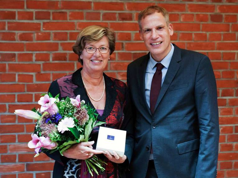 Eine Frau mit Blumenstrauß in der Hand und ein Mann.