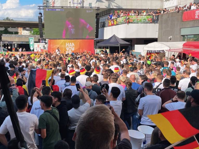 Menschen auf einem Platz schauen ein Deutschland-Spiel.