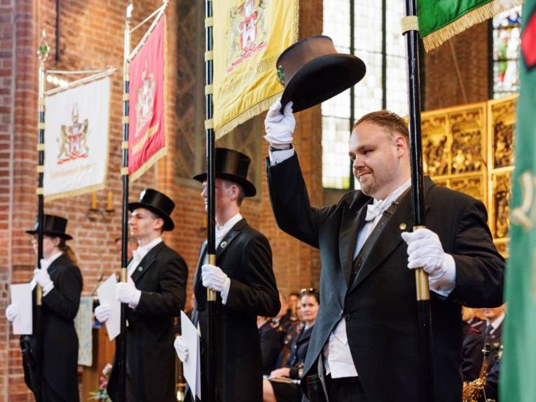 Vier Personen mit Standarten in einer Kirche.