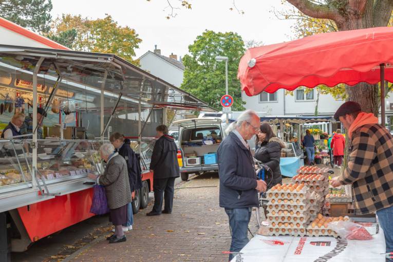 Blick zwischen die Marktstände: Kundschaft und Verkaufspersonal auf dem Wochenmarkt