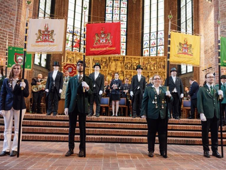 Vier Personen mit Standarten in einer Kirche.