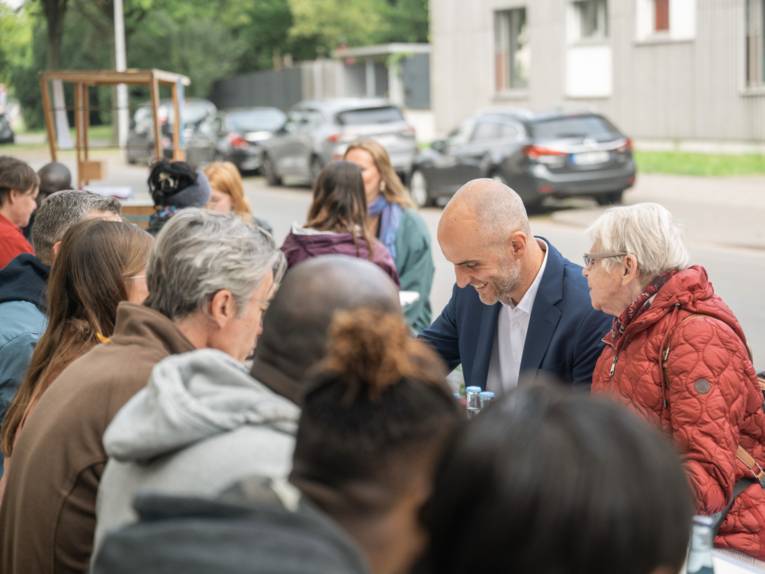 Viele Menschen sitzen an einem Tisch und lachen.