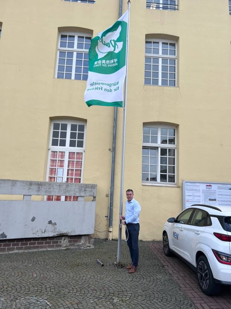 Ein Mann hisst die Mayors-for-Peace-Flagge