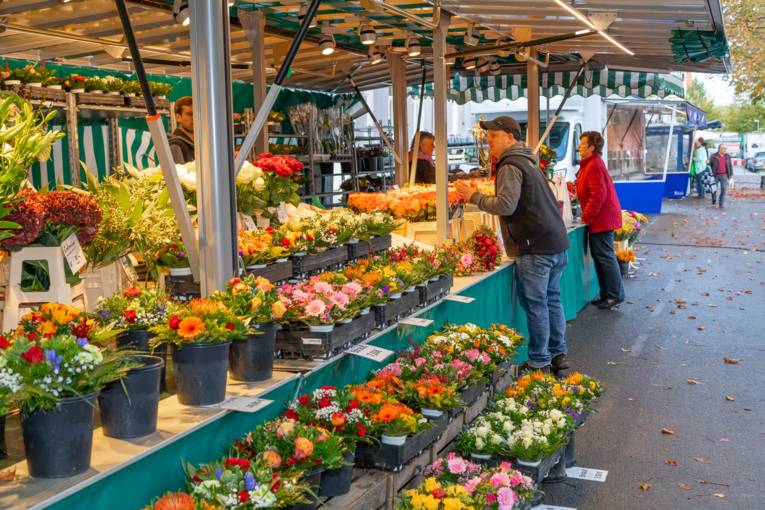 Menschen an einem Blumenwagen auf dem Wochenmarkt.